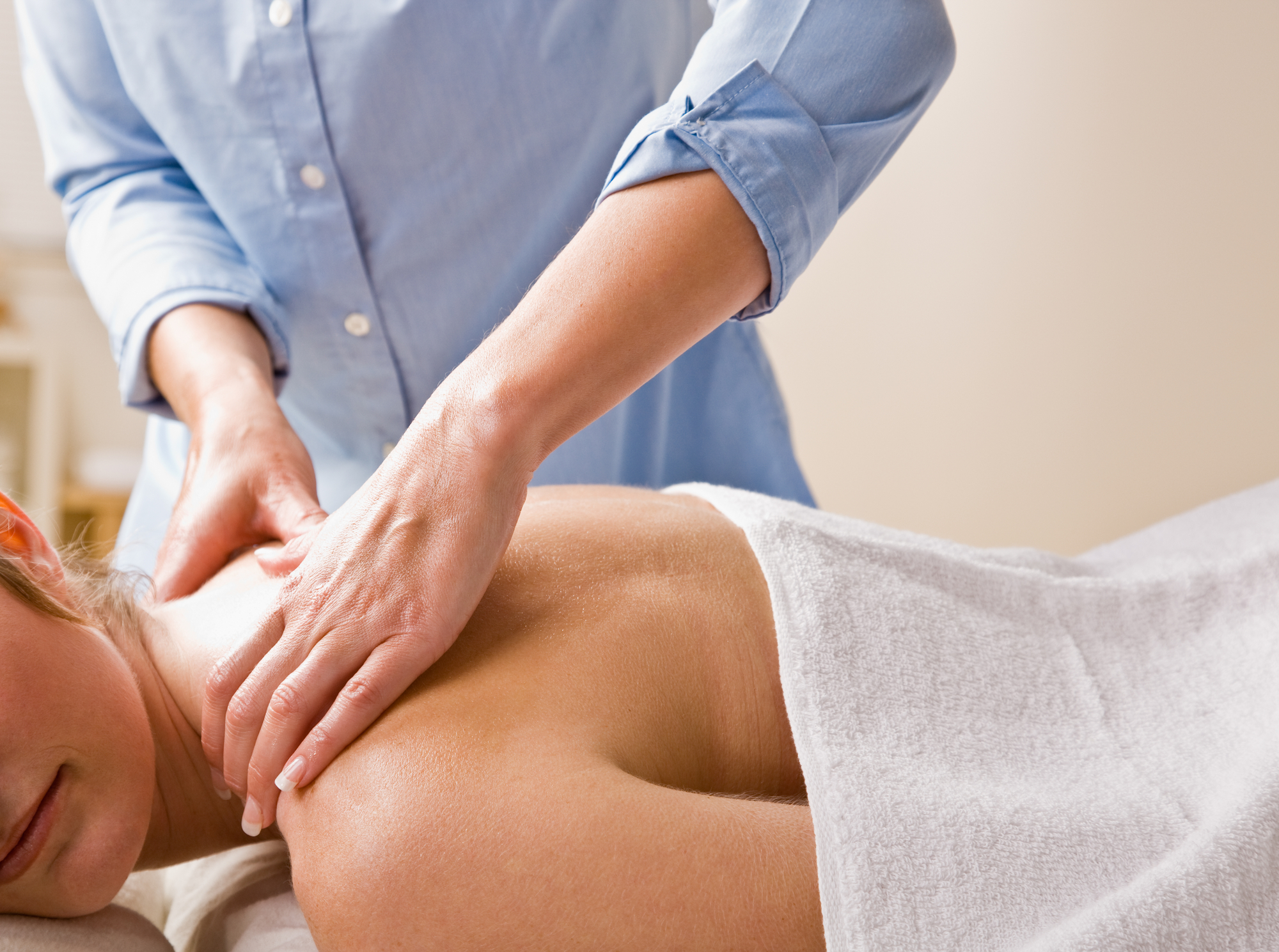Therapist pressing into the muscles between a client's neck and shoulder blade