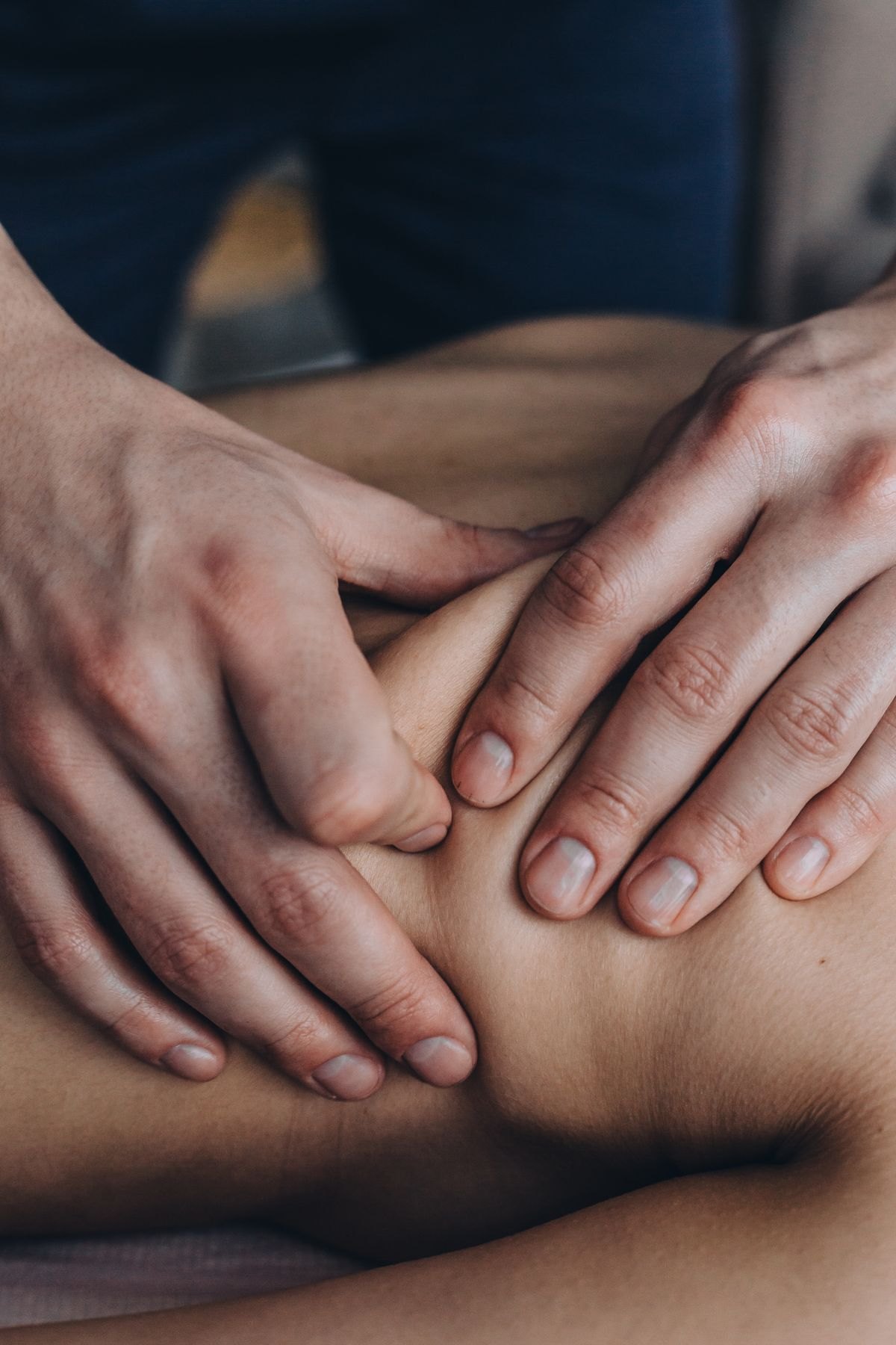 Therapist applying deliberate pressure to a client's upper back during a massage session