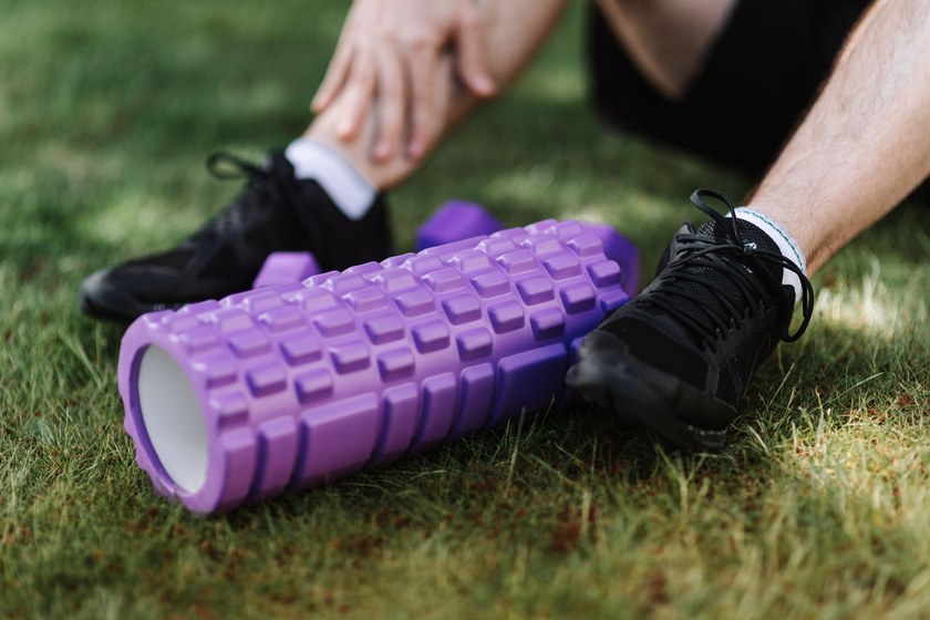 Foam roller and running shoes on grass after a training session