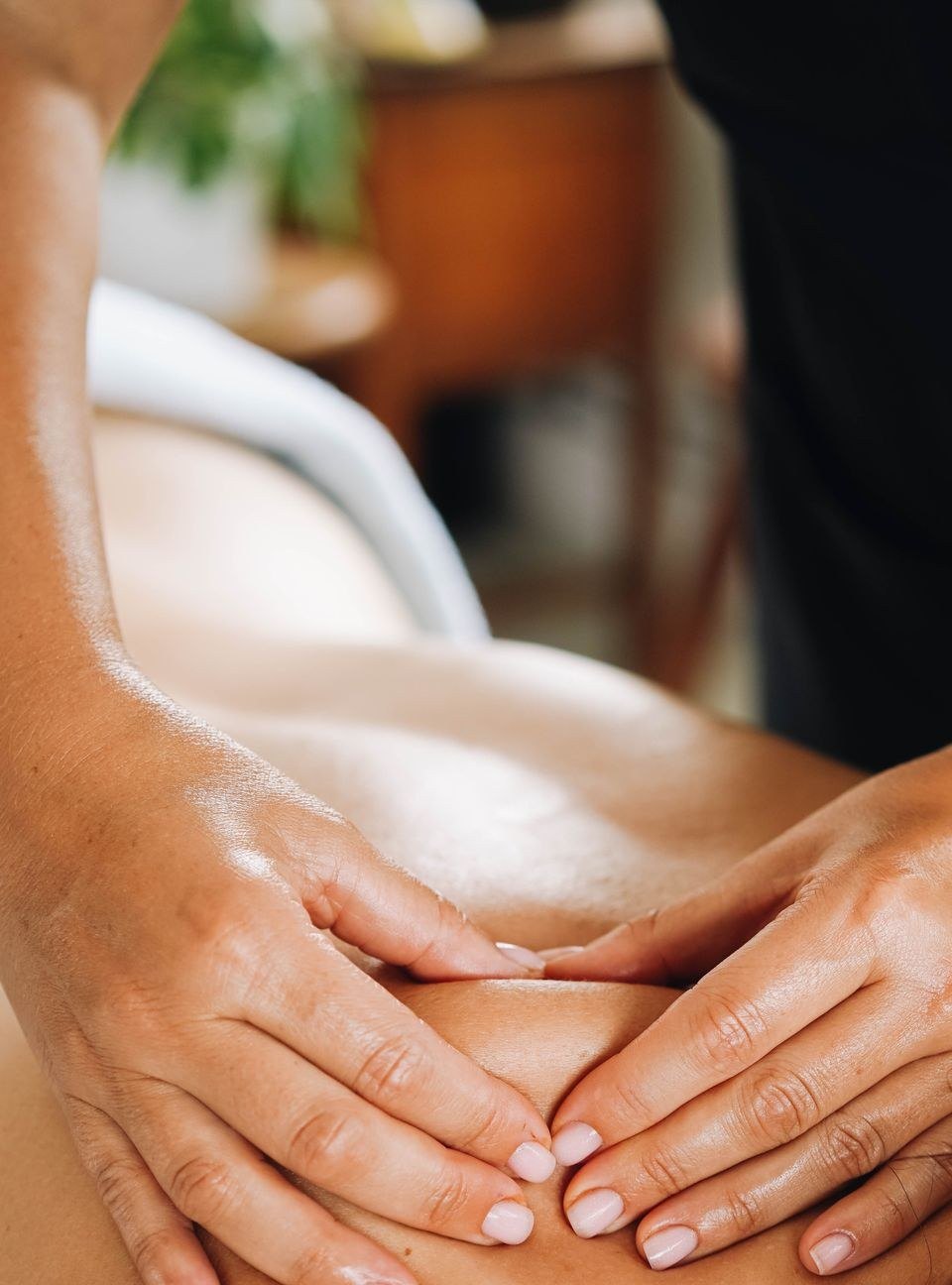 Close view of a massage therapist working along a client's upper back